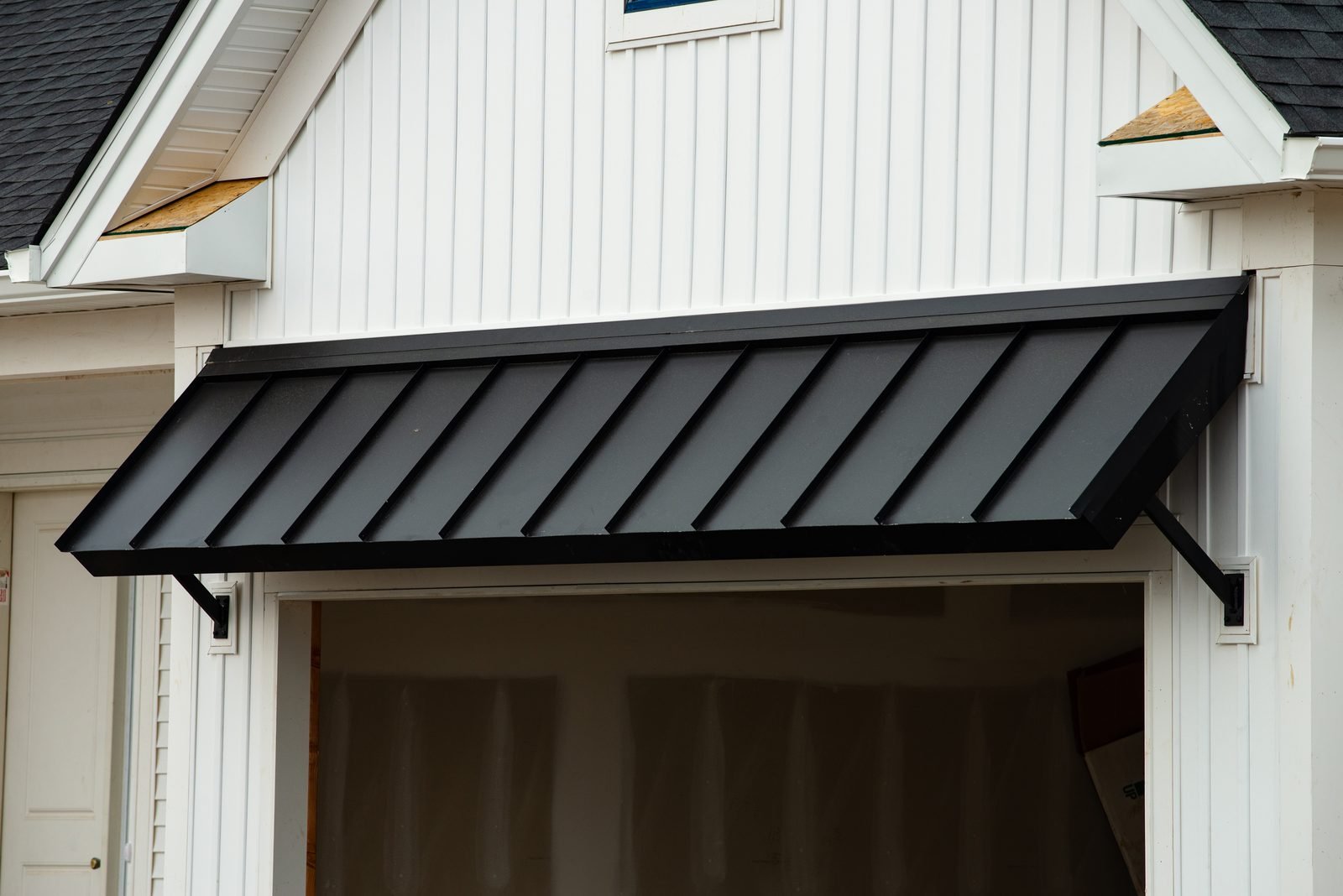 Black metal awning over a white siding facade