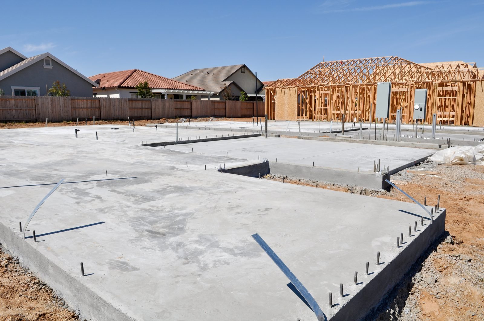Poured slab foundation with framed houses in the background